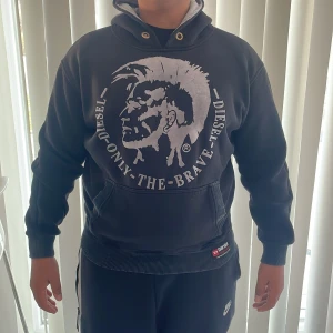 Svart hoodie från Diesel - Säljer en svart hoodie från Diesel med ett stort tryck av en profil och texten 'Only The Brave' på framsidan. Storlek M passar folk 175 - 180 och skick 8/10! Tröjan har en klassisk känguruficka och ribbade muddar vid ärmslut och nederkant. Perfekt för en avslappnad stil ✅