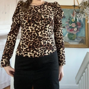 Leopardmönstrad topp med puffärmar - Säljer en snygg leopardmönstrad topp med puffärmar. Toppen har en figurnära passform och är perfekt för att sticka ut. Den är långärmad och har en rund halsringning.