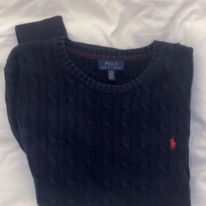 Ralp Lauren tröja - Hej. Säljer en snygg mörkblå stickad tröja från Ralph Lauren. Tröjan är i mycket fint skick och är i storlek 18-20 vilket motsvarar M. Hör av dig vid frågor och funderingar! Pris inte hugget i sten.