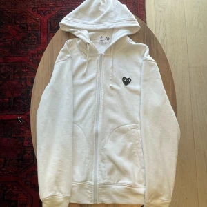 Vit CDG Kofta - Vit CDG hoodie med zip, storlek M. Sparsamt använd, väldigt bra skick. Pris kan diskuteras!