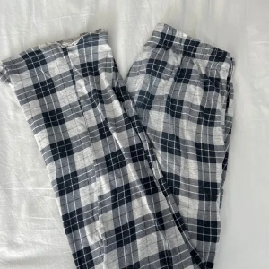 Rutiga pyjamasbyxor  från Kappahl - Säljer ett par bekväma rutiga pyjamasbyxor från Kappahl i storlek S. Byxorna har ett klassiskt svart och vitt rutmönster och är utrustade med en praktisk snörning i midjan för bästa passform.