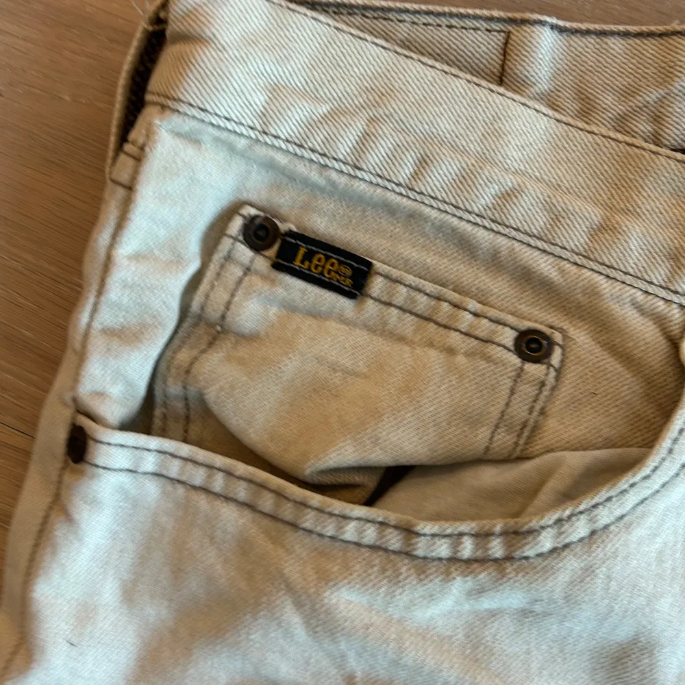 Snygga beige jeans från Lee med klassisk femficksdesign. De har en rak passform och är perfekta för en avslappnad stil. Märkesloggan syns tydligt på bakfickan. Perfekt för dig som gillar en tidlös look. Mått finns i bild . Farkut & Housut.