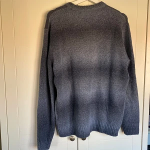 Grå stickad tröja - Säljer en stilren grå stickad tröja med rund hals och långa ärmar. Perfekt för kyliga dagar och enkel att matcha med olika outfits. Tröjan har en mjuk och bekväm passform. Passar M