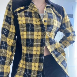 Gul och svart rutig jacka - Snygg gul och svart rutig jacka med knappar framtill. Jackan har långa ärmar och en klassisk krage. Ger clueless vibes