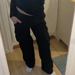 Svarta cargobyxor - Säljer ett par svarta cargobyxor med flera fickor och en loose passform från H&M. Byxorna har elastisk midja för extra komfort och är perfekta för en avslappnad stil. Strlk 36. Säljer då de inte kommer till användning. 