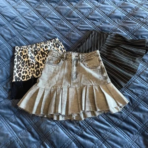 Tre snygga kjolar i olika stilar - Säljer tre olika kjolar: en leopardmönstrad kortkjol med svart spetsdetalj, en svart kortkjol med vita ränder och en jeanskjol med volang. Perfekta för att mixa och matcha till olika tillfällen!💕🎶