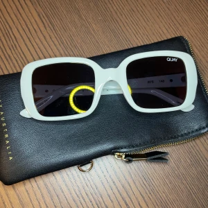 Vita solglasögon från Quay - Snygga vita solglasögon från Quay med en fyrkantig form. Kommer med ett svart fodral med dragkedja. Helt oanvända.