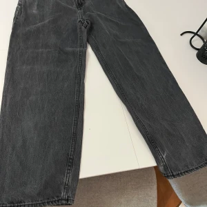 Svarta raka jeans från HM Loose fit - Säljer ett par svarta jeans från Levi's med klassisk femficksdesign och raka ben. Jeansen har en snygg tvättad look och är tillverkade i slitstarkt bomullsjeans. Perfekta för dig som gillar en tidlös och avslappnad stil.