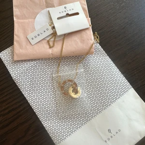 Guldigt halsband från Edblad - Supersnyggt halsband från Edblad i guldton med två sammankopplade cirklar. Helt nytt, aldrig använt. 