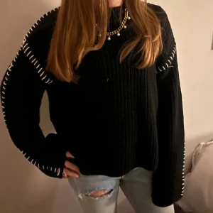 Svart stickad tröja med vita detaljer - Svart stickad tröja från Gina Tricot med vita sömdetaljer längs axlar och ärmar. Tröjan har en loose passform, ribbad struktur och långa ärmar. Perfekt att matcha med jeans för en chill look.