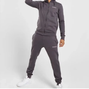 McKenzie  - Snygg grå hoodie från McKenzie med dragkedja och ribbade muddar. Och mjukis byxor till som matchar. Perfekt för en avslappnad stil. Den har en klassisk passform och är tillverkad i mjukt material för extra komfort.