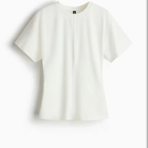 Vit kortärmad blus med rak passform - En stilren vit blus med korta ärmar och rund hals. Toppen har en rak passform och en diskret söm framtill som ger en clean look. Perfekt att matcha med både jeans och kjol för en enkel men snygg outfit. Pris lapp kvar och endast provad, säljer då den inte var i rätt storlek. 