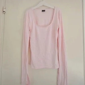 Ljusrosa långärmad topp med djup ringning - Supersöt ljusrosa långärmad topp med djup, rundad ringning. Sitter tight och framhäver figuren, perfekt att styla med jeans eller kjol. Tunn och mjuk i materialet, enkel men ändå riktigt snygg och feminin.