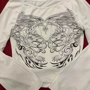 Vit långärmad topp med tryck - Säljer en vit långärmad topp med svart tryck. Mycket bra skick och helt oanvänd! Fråga mig om ni undrar något ^^