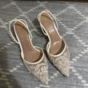 Beige spetsiga pumps med broderi från Zara - Eleganta pumps från Zara i beige med spetsig tå och låg klack. Skorna har vackert blommigt broderi och pärldetaljer på.