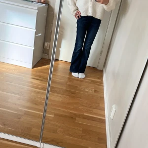 Mörkblå bootcut jeans från ginatricot - Snygga mörkblå jeans från ginatricot med klassisk bootcut passform och broderad bakficka. Jeansen har normal midja, fem fickor och är tillverkade i slitstarkt denim. Storlek 146/