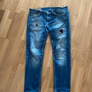Dondup Jeans - Tjena, säljer nu ett par riktigt snygga Dondup jeans med snygga slitningar. Jeansen är i storlek 34 men passar även 33 . Jeansen är i bra skick förutom ett litet hål vid skrevet som enkelt går att laga. Om ni har några frågor är det bara att skriva!