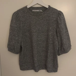 Grå stickad tröja från 157 - Mysig grå stickad tröja från 157 med rund halsringning och trekvartsärmar. Perfekt för lager-på-lager och chill dagar. Enkel och stilren design som funkar till det mesta. Snyggt melerat tyg som ger en soft vibe.