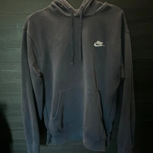 Marinblå Nike hoodie - Snygg marinblå hoodie från Nike med klassisk logga på bröstet. Tröjan har huva med snörning och en magficka. Perfekt för dig som gillar en enkel och stilren look.