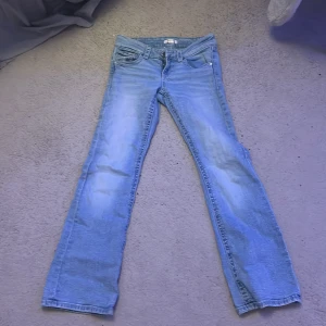 Ljusblå bootcut jeans Gina Tricot  - Snygga ljusblå jeans från Gina Tricot i storlek 152. Modellen har klassisk femficksdesign och bootcut-ben som ger en retrovibe. Jeansen är tillverkade i mjukt denimtyg och har en normal passform. Perfekta till sneakers eller boots.