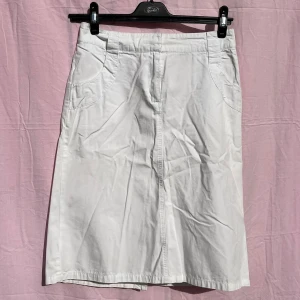 Vit bomullskjol från H&M, stl 36 - Vit, stilren kjol från H&M i 100% bomull. Kjolen har normal passform, praktiska fickor fram och bälteshällor i midjan. Längden går till knäna och modellen är klassisk och enkel, perfekt för en clean look.