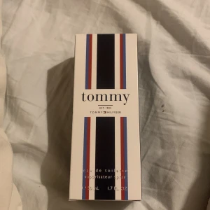 Tommy Hilfiger Tommy EdT 50ml - Fräsch parfym från Tommy Hilfiger, 'Tommy', i en stilren glasflaska med silverfärgad kork. Kommer i originalkartong med klassiska ränder i blått, rött och vitt. Flaskan rymmer 50 ml eau de toilette och har en modern, enkel design.