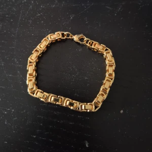 Chunky guldarmband med kedjelänkar - Snyggt chunky armband t stol guld med rejäla, rektangulära kedjelänkar och karbinlås. Perfekt statement piece som lyfter vilken outfit som helst. Armbandet har en modern och stilren design med glänsande finish.