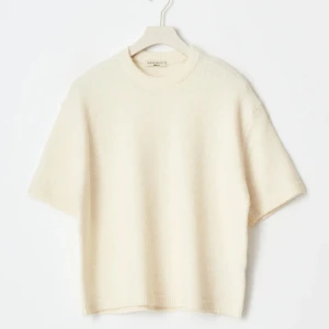 Krämvit stickad tröja från Gina  - Säljer en krämvit stickad tröja från Gina  med rund hals och korta ärmar. Tröjan har en loose passform och är tillverkad i mjukt material som känns lyxigt mot huden. Perfekt att styla med jeans eller kjol för en clean look.