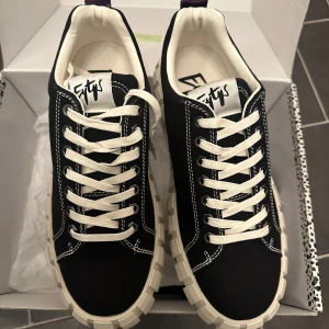 Svarta Eytys Odessa sneakers med chunky sula 42 - Säljer ett par svarta Eytys sneakers med vit chunky sula och kontrasterande vita sömmar. Skorna har vit snörning, rund tå och är tillverkade i canvas med grov yttersula i gummi. Logotypen syns på plösen och innersulan. Perfekt för dig som gillar streetstyle.
