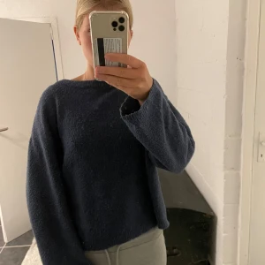 Mörkblå stickad tröja från 157 - Mysig mörkblå stickad tröja från 157 med rund halsringning. Tröjan har långa ärmar och är perfekt för kyligare dagar. Enkel och stilren design som är lätt att matcha med olika outfits.