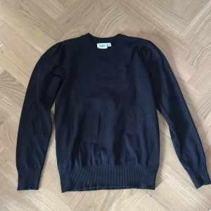 Svart tröja från Saint Tropez - En svart, klassisk tröja från Saint Tropez i storlek S. Tröjan har rund halsringning, ribbade muddar och lång ärm. 