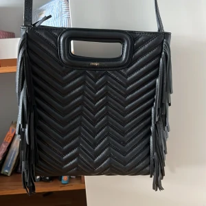 Svart quiltad axelväska från Maje - Snygg svart axelväska från Maje i quiltat skinn med chevronmönster. Väskan är i väldigt fint skick och ändast använd fåtal gånger  därav pris, köpt för 3000 i nypris🥰dustbag tillkommer även