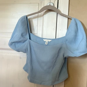 Ljusblå ribbad topp - Superfin ljusblå ribbad topp från H&M med puffiga korta ärmar och fyrkantig urringning. Croppad modell och väldigt fin!