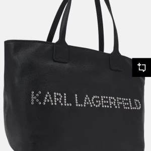 Svart axelväska från Karl Lagerfeld - Snygg svart axelväska från Karl Lagerfeld med logotyp i silverdetaljer. Väskan har två handtag och en dragkedja upptill för säker förvaring. Perfekt för att bära med sig det nödvändigaste med stil. Materialet är läder! Mått (47*30*18) handtag 23 cm. Ord. 3500 sek.