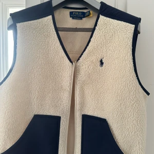 Vit fleeceväst från Polo Ralph Lauren - Snygg vit fleeceväst från Polo Ralph Lauren !! Säljer åt en kompis - bra skick 💕💕💕 den hade en mindre fläck på bröstet men den är borttvättad nu, så första bilden är hur den ser ut nu när fläcken är borta, pris kan diskuteras 