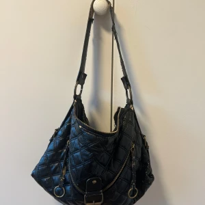 Svart quiltad axelväska - Snygg svart axelväska med quiltat mönster och dragkedja. Fräsch på innefodret, inga fläckar eller hål, säljer billigt så buda gärna ☺️