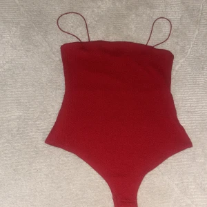 Röd bodysuit från H&M - Snygg röd bodysuit från H&M med smala axelband. BARA TESTADE ALDIRG ANVÄND!!!