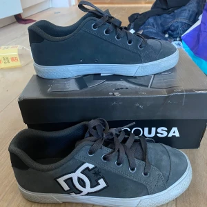 Gråa sneakers från DC - Snygga svarta sneakers från DC med vit sula och klassisk snörning. Skorna har en rund tå och är perfekta för en avslappnad stil. DC-loggan syns tydligt på sidan av skorna. Sjukt ledsen över att jag ska sälja dessa men dem är för små för mig 😔