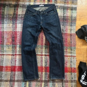 Mörkblå selvedge  jeans från Acne Jeans - Snygga mörkblå jeans från Acne Jeans med klassisk femficksdesign och knappgylf. Perfekta för en stilren look. Tillverkade i högkvalitativt denim.