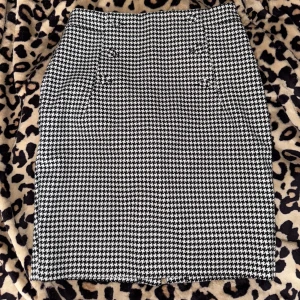 Svartvit rutig kjol - Snygg svartvit rutig kjol med knappar fram till.  Kjolen har en slits baktill och en dragkedja för enkel på- och avtagning.