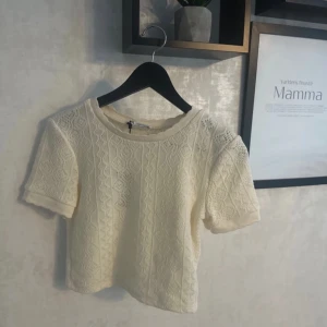Vit spetsblus från Zara - Säljer en söt vit spetsblus från Zara. Blusen har korta ärmar och ett vackert spetsmönster som ger en romantisk känsla. Perfekt för vår och sommar!