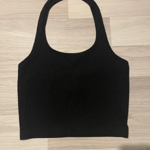 Svart ribbad halsternecktopp - Snygg svart ribbad halsternecktopp. Perfekt för en stilren look och kan matchas med olika outfits. Enkel och tidlös design.