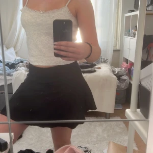 Svart kortkjol - Snygg svart kortkjol med en enkel och stilren design. Perfekt för att matcha med olika toppar och accessoarer. Kjolen har en lätt utställd form som ger en fin siluett.