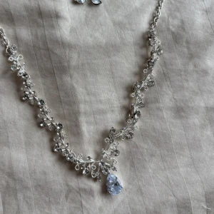 Silverfärgat halsband och örhängen med kristaller - Elegant set med ett silverfärgat halsband och matchande örhängen, dekorerade med gnistrande kristaller.  (inte äkta diamant eller silver)