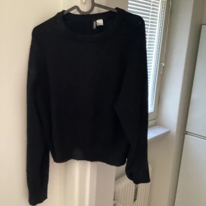 Svart stickad tröja från H&M - Säljer en klassisk svart stickad tröja från H&M. Tröjan har en rund halsringning och långa ärmar, perfekt för kyligare dagar. Enkel och stilren design som passar till det mesta.