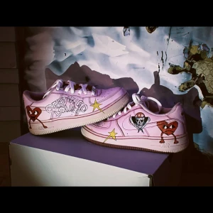 Rosa Nike Air Force med handmålade detaljer - Unika rosa Nike Air Force med handmålade hjärtan och stjärnor. Skorna har en klassisk siluett med snörning och rund tå. Perfekt för dig som vill sticka ut med en personlig touch.