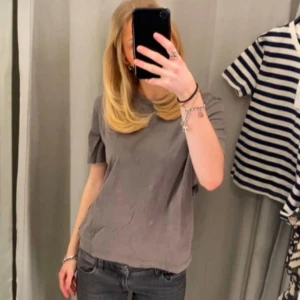 Grå t-shirt - Säljer en enkel och stilren grå t-shirt med rund hals och korta ärmar. Perfekt för en avslappnad look. Passar bra till jeans eller shorts.