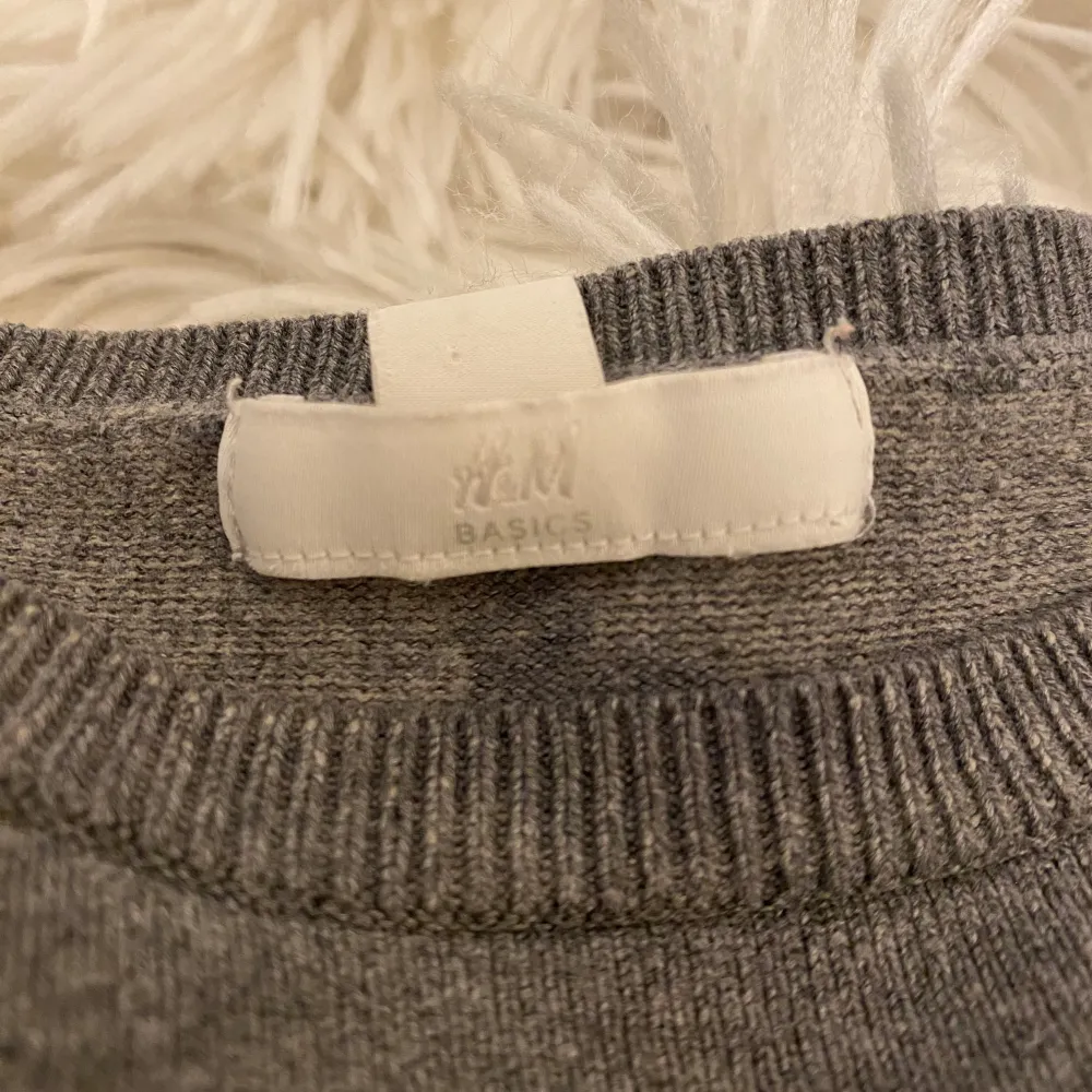 Säljer en stilren grå tröja från H&M Basics. Tröjan har en klassisk rund hals och långa ärmar, perfekt för en enkel och bekväm look. Ribbstickade muddar vid ärmslut och nederkant ger en snygg finish.. Neuletakit & Villapaidat.