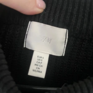 Svart och vit randig tröja från H&M - Säljer en snygg svart och vit randig tröja från H&M. Tröjan är stickad och har långa ärmar med en croppad passform. Perfekt för en stilren look!