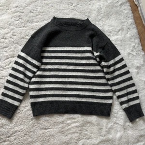 Grå och vit randig tröja - Snygg grå tröja med vita ränder. Den har en klassisk rund hals och långa ärmar. Perfekt för en stilren look.